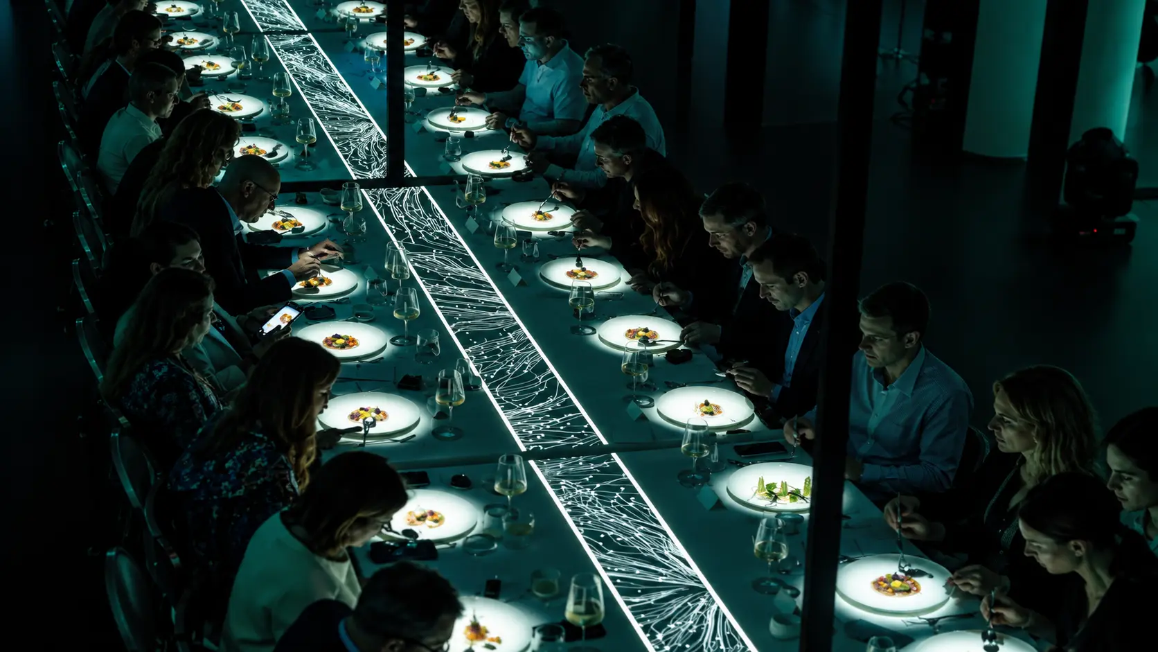 Guests gathered around a table illuminated with graphic projections
